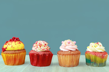 Tasty cupcakes on wooden table and spruce color background