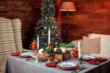Beautiful Christmas family dinner table at the nicely decorated New Year interior with Christmas tree