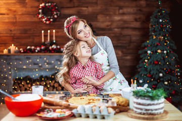 Merry Christmas and Happy Holidays. Family preparation holiday food. Mother and daughter cooking cookies in New Year interior with Christmas tree.
