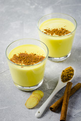 Winter warming healing cinnamon turmeric milk on stone background. Selective focus, space for text. 