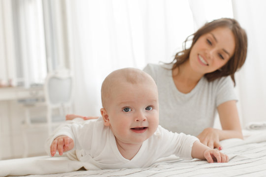 Mother and baby playing and smiling on the bed happy family. Boy looking at camera