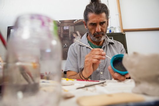 Attentive man painting bowl - Powered by Adobe