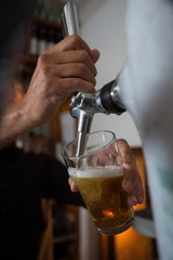 Fototapeta na wymiar Brewer filling beer in beer glass from beer pump in bar