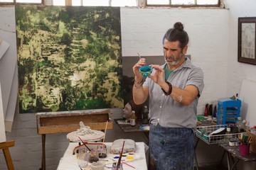 Attentive man painting bowl