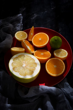still life from a mix of exotic fruit of citrus fruits and lobules on a dark background with sun rays and shadows. a color shot of fruit with space for text.