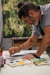 Attentive man painting at table