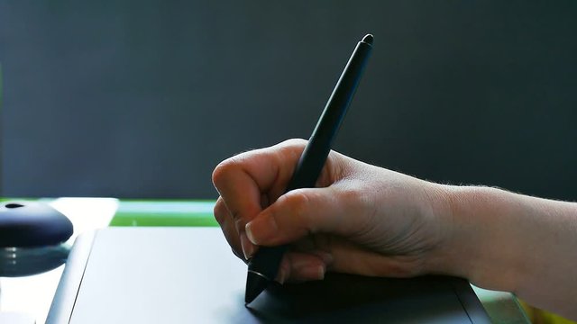 Tablet and pen, black background.Woman working with tablet and pen for post production .