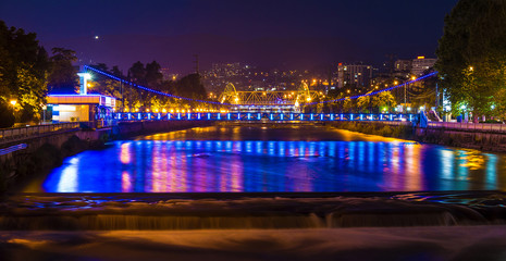 Night panoramic view of illuminated Malyy Kubanskiy bridge and Sochi river with lights reflected in its water, Sochi, Russia
