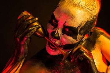 Pretty girl with skeleton makeup holds glass