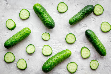 Fresh cucumbers and cucumber slices on grey background top view