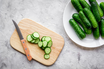 Cut fresh cucumbers on cutting board. Grey background top view