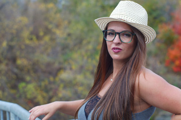young girl in her twenties wearing hat and glasses portrait outdoor sunshine
