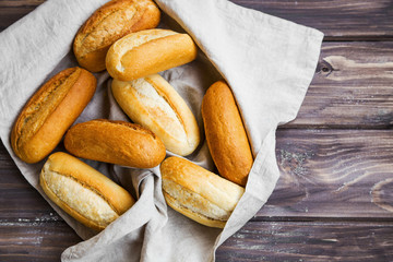 Fresh bread buns in a towel on wooden board