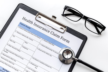 Health insurance for reception at the doctor. Document, stethoscope, pad, glasses on white background top view