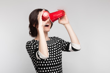 Picture of attractive woman in speckled clothes standing with cup in hands