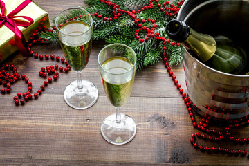 Fototapeta na wymiar Champagne for celebrate new year. Glasses, bottle in bucket, spruce branch, decoration on wooden background