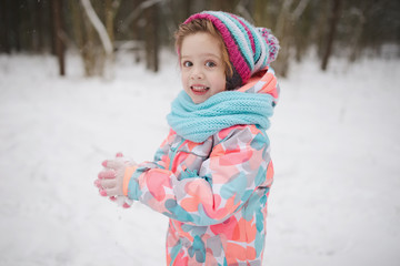 cute little girl plays with snowballs