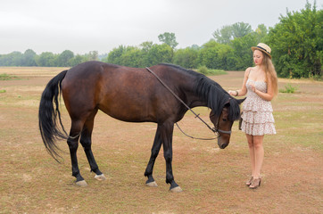 Girl in a straw hat and summer dress with a horse / Photographed in Russia, at the racetrack in Orenburg