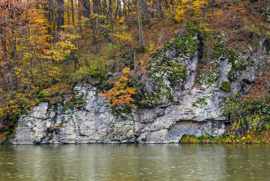 rocky cliff above the river in autumn forest. stunning nature scenery