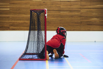 Unidentifiable floorball goalkeeper during mach. Child boy player scoring during the floorball match. Children playing floorball