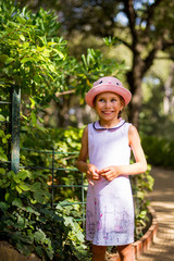Pretty girl in a hat posing while having fun in park in summer vacation.