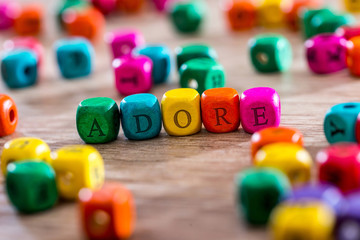 adore - word created with colored wooden cubes on desk.