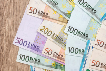 mant euro bills on wooden desk. close up