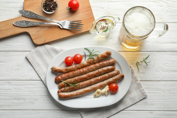 Plate with delicious grilled sausages on table