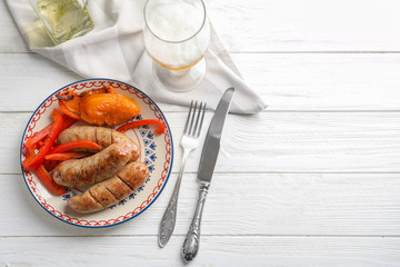 Plate with delicious grilled sausages on wooden background