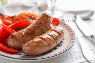 Plate with delicious grilled sausages on table