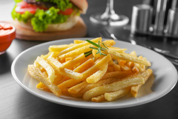 Plate with yummy french fries on table