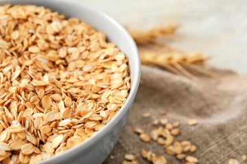 Bowl with raw oatmeal on table, closeup
