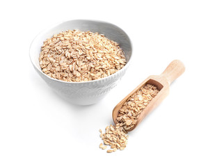 Bowl with raw oatmeal and scoop on white background