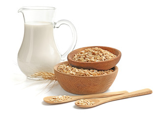 Composition with raw oatmeal and jug of milk on white background