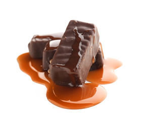 Sweet chocolate candies with caramel topping on white background