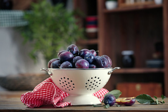 Fresh plums in colander on table