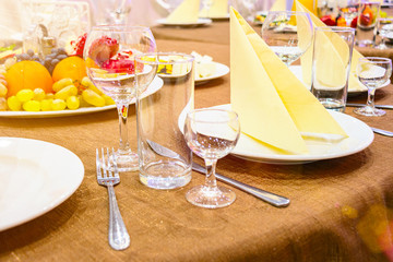 The table in the restaurant. On the table there are empty wine glasses, napkins and plates. Also in the picture you can see fruit plate