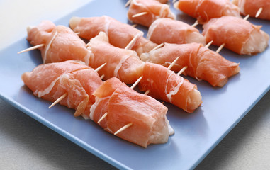 Plate with raw bacon wrapped chicken, closeup