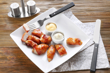 Plate with bacon wrapped chicken on table