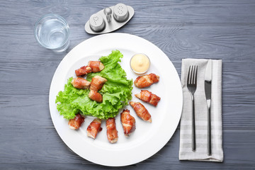 Plate with bacon wrapped chicken on table