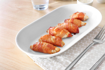 Plate with bacon wrapped chicken on table
