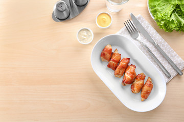 Plate with bacon wrapped chicken on table