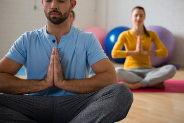 Yoga instructor with student meditating in prayer position at