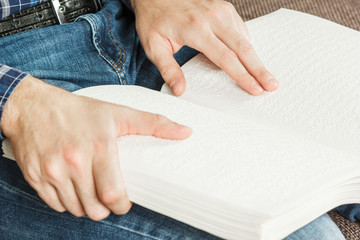 The blind man was reading a book written on Braille. Touch your finger on the braille code. A book...