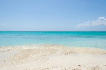 Fototapeta na wymiar Turquoise sea water with white sand rock beach and blue sky. Horizon line, Turks and Caicos Islands.