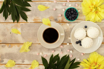 Morning coffee, marshmallows and beautiful yellow peony flowers on light table top view in flat lay style. Cozy breakfast on Mother or Woman day.