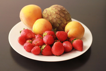 Fototapeta na wymiar white plate with fruits strawberry peaches anon