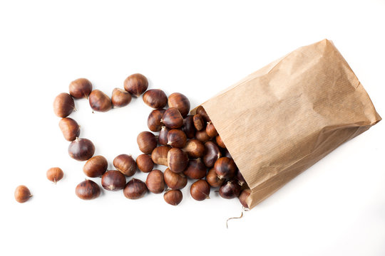 edible chestnuts - a bag of fresh, raw chestnuts sprinkled on a white background