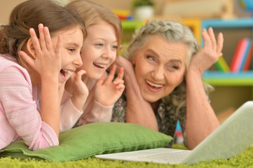 senior woman with granddaughters using laptop