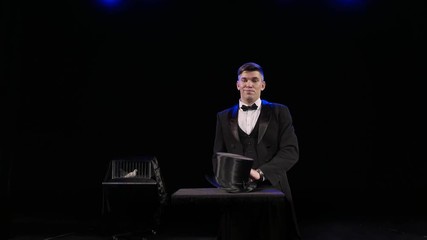 A man dressed as a magician pulling a rabbit from his hat